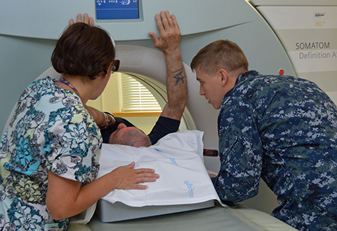 Anna Almeida-Tenreiro, a radiology technologist, and Navy hospital corpsman Petty Officer 3rd Class Kanoa LaVoun prepare World War II Navy Veteran Hector R. Rosado for a CT scan