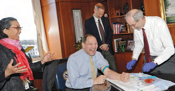Kyong-Mi Chang, Acting Chief Research and Development Officer and John Concato, MVP Principle Investigator look on and laugh as Bob McDonald, Secretary, Dept. of Veterans Affairs has his blood drawn by J. Michael Gaziano, MVP Principal Investigator.