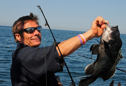 Mark Sanders, a U.S. Marine Corps Veteran from Manomet, Mass., shows the black sea bass he just caught off of Point Judith, R.I., Thursday, July 21, 2016, during the VA New England's Adaptive Summer Sports Clinic